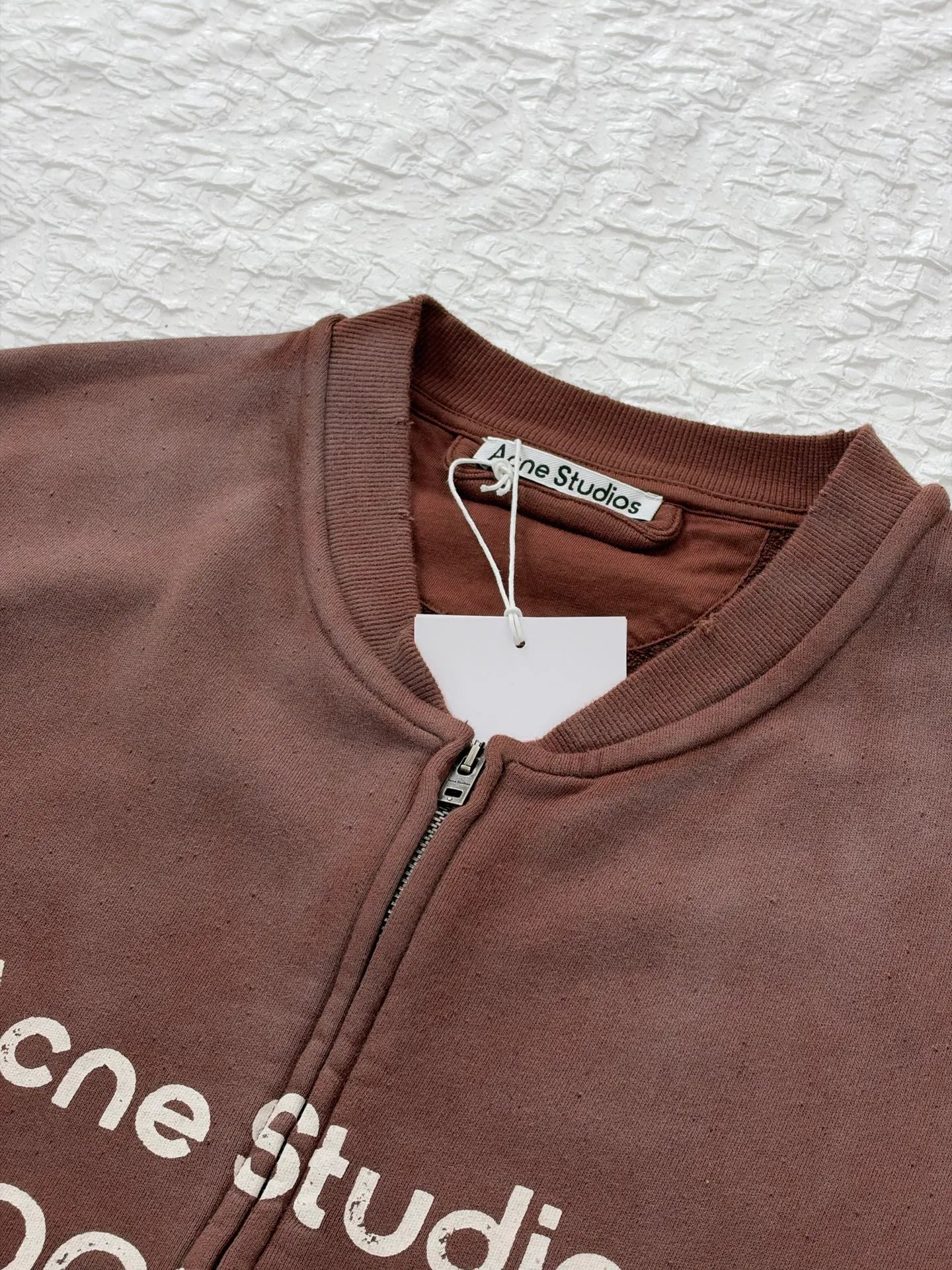 Acne Studio distressed washed zipper baseball sweatshirt is made of 100% cotton terry cloth, garment washed + distressed and sanded. The body adopts dropped shoulder sleeves, a loose oversize silhouette, a V-shaped ribbed baseball collar design, and the edge of the collar is deliberately frayed and damaged. The main zipper is made of distressed metal zipper, and the front panel is positioned with glue crack printing. Size: S/M/L/XL